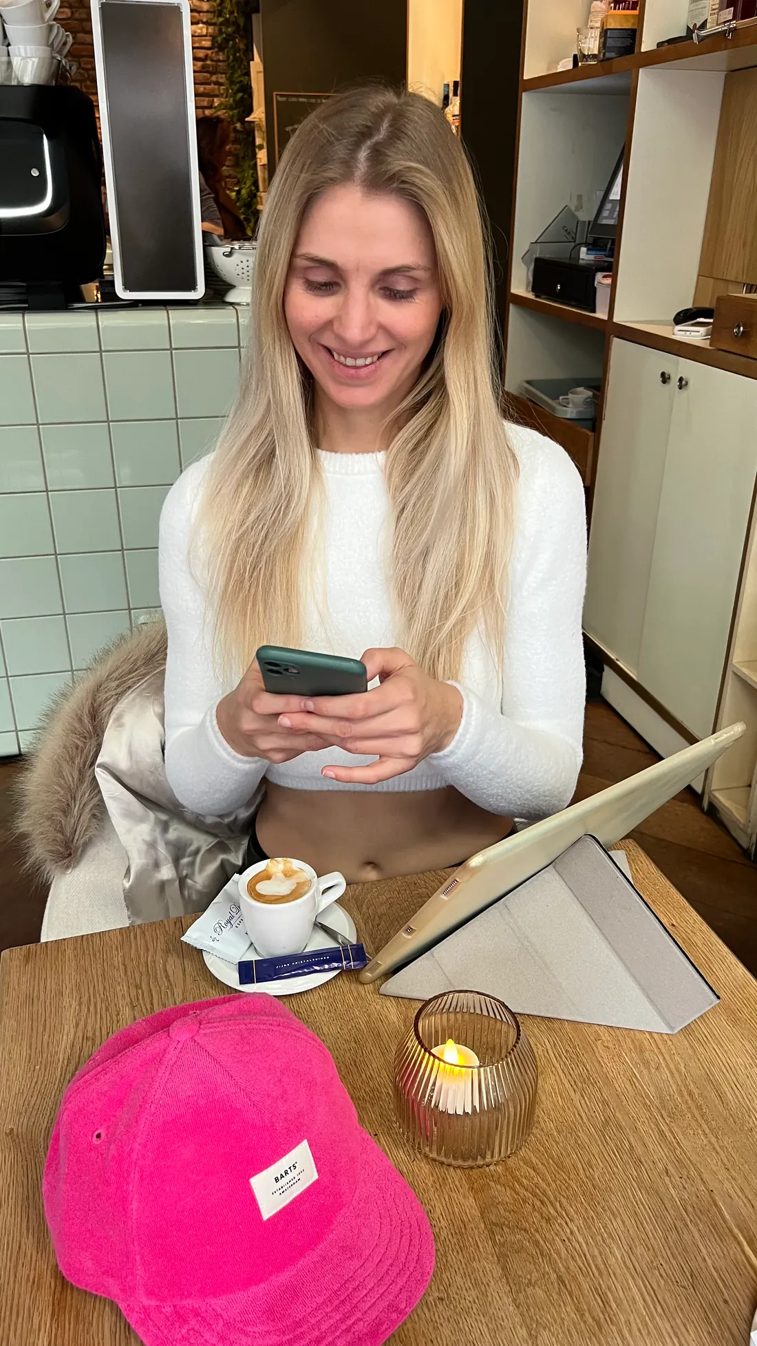 Anaïs, sourire, sur son téléphone dans un café, en train de tenir une routine