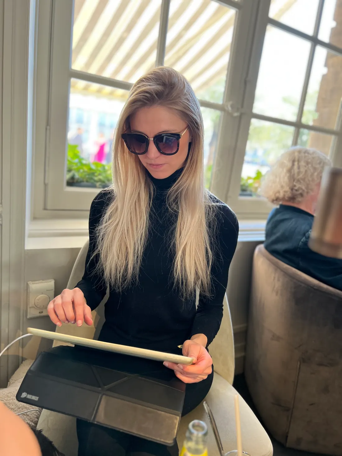 Anaïs, lunettes de soleil, tablette en main